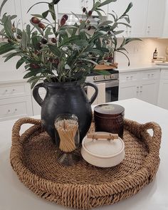 a large black vase sitting on top of a wicker tray next to a potted plant