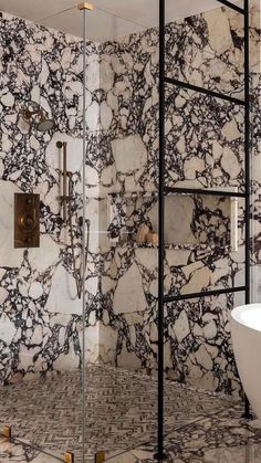 a bathroom with black and white marble on the walls, flooring and bathtub