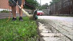 a man is using a lawn mower to cut grass on the side of a road