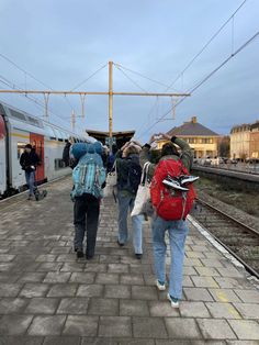 several people are walking on the train tracks with their backpacks up to their backs