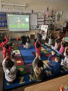 a group of children sitting on the floor in front of a projector screen