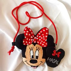 a minnie mouse ornament hanging from a red string on top of a white sheet