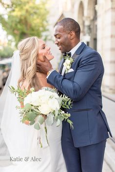 a bride and groom standing together on the street