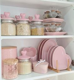 the shelves are filled with pink dishes and other kitchenware, such as glass jars