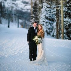 a bride and groom standing in the snow