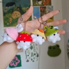 three small crocheted gnome keychains hanging from a person's hand