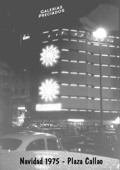 a black and white photo of cars parked in front of a tall building at night