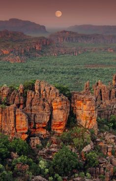 the full moon is setting over the rocky terrain in australia's outback region