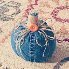 a blue jean pumpkin with a button on it sitting on a white rug in the middle of a room