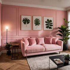 a living room with pink walls and two paintings on the wall above the couches