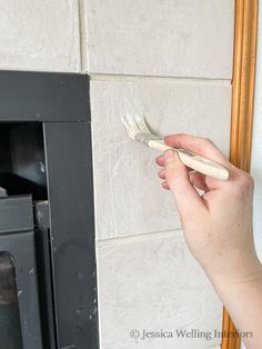 a person holding a paintbrush in front of a fireplace