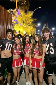 the cheerleaders are posing for a photo in front of a palm tree at night