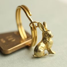 a gold rabbit keychain sitting next to a cell phone