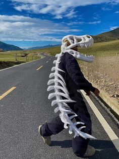 a man is walking down the road with a fake dinosaur skeleton on his head and tail