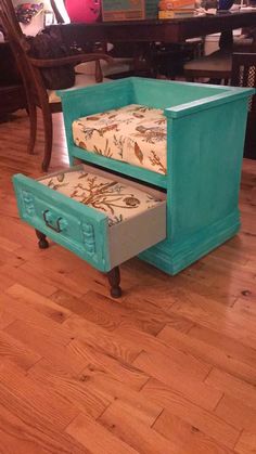 an old bed with a drawer underneath it on the floor in front of a table and chairs