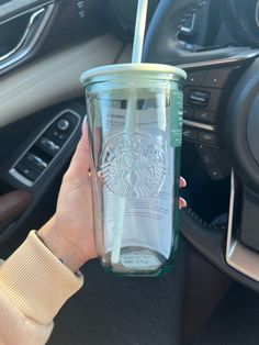 a woman is holding a starbucks cup in her hand while she sits in the driver's seat