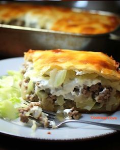 a white plate topped with a casserole covered in meat and cheese