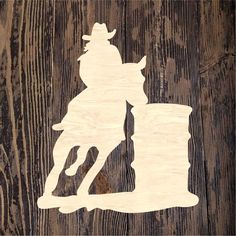 a wood cutout of a cowboy riding a horse on a wooden background with text