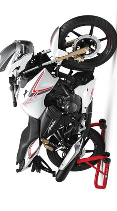 a white motorcycle with red and black accents on it's front wheel is suspended upside down