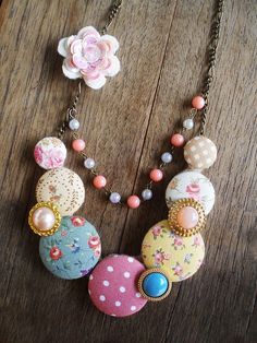 a necklace with flowers and beads hanging from it's side on a wooden table