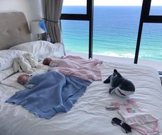 a baby laying on top of a bed under a blanket next to two stuffed animals