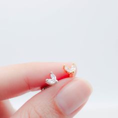 a person's hand holding a tiny ring with two small leaves on the side