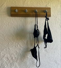 three black bras hanging on a wooden coat rack with two hooks and one hook