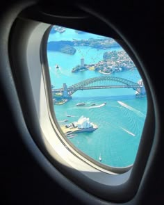 an airplane window with the view of sydney harbour and bridge in the distance, taken from inside