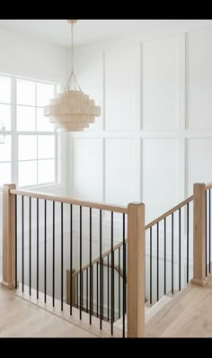 an empty room with white walls and wood railings, chandelier hanging from the ceiling