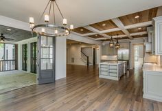 a large open floor plan with wood floors and white cabinetry, chandelier over the kitchen island