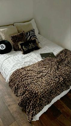 a leopard print comforter on a bed in a room with wood floors and white walls