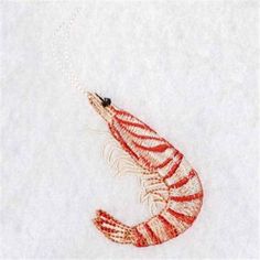 a red and white shrimp is hanging from a chain on a white surface with snow in the background