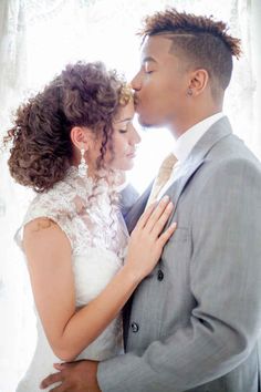 a young man and woman are kissing each other in front of a white curtained window