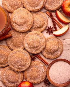 apple cider cookies, cinnamon sugar and apples on a wooden table with an apple in the background