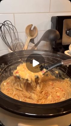 a slow cooker filled with noodles and cheese being stirred by a ladle in it