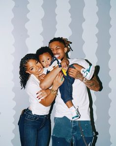 a man and two women are hugging each other while the woman is holding a baby in her arms