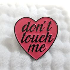 a pink heart shaped pin with the words don't touch me on it