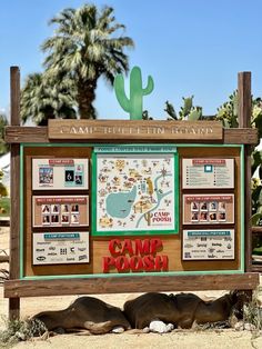 a sign that is in the sand near some cactus plants and trees, with information about how to get there