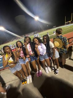 a group of young women standing next to each other on a baseball field at night