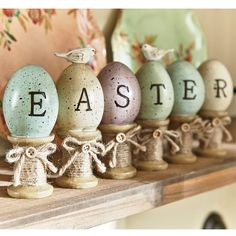 an assortment of painted eggs with the word easter written on them sitting on a shelf