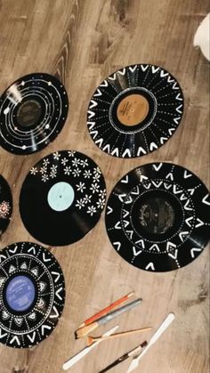 several black and white plates sitting on top of a wooden floor next to paintbrushes