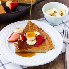 a piece of french toast on a plate with fruit and syrup being drizzled over it