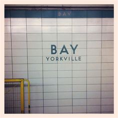 the sign on the wall says bay yorkvillee in blue and white tiles,