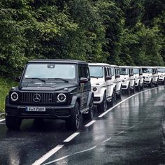 a line of cars parked on the side of a road in front of some trees