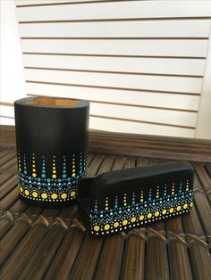 two black and yellow vases sitting on top of a wooden table next to each other