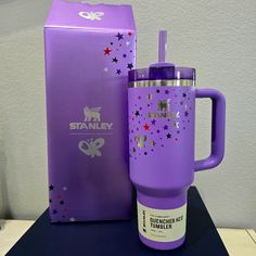 a purple travel mug sitting next to a cardboard box