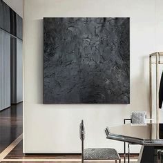 a black and white painting hanging on the wall in a dining room next to a glass table