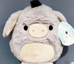 a stuffed animal with a tag attached to it's ear and nose, sitting against a gray background