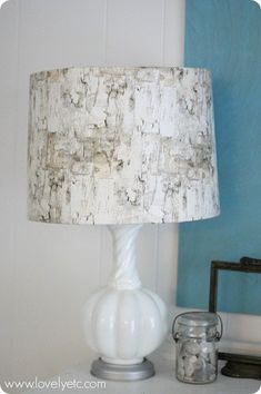 a white lamp sitting on top of a table next to a glass jar filled with rocks