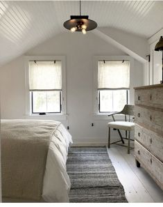 a bedroom with white walls and two windows